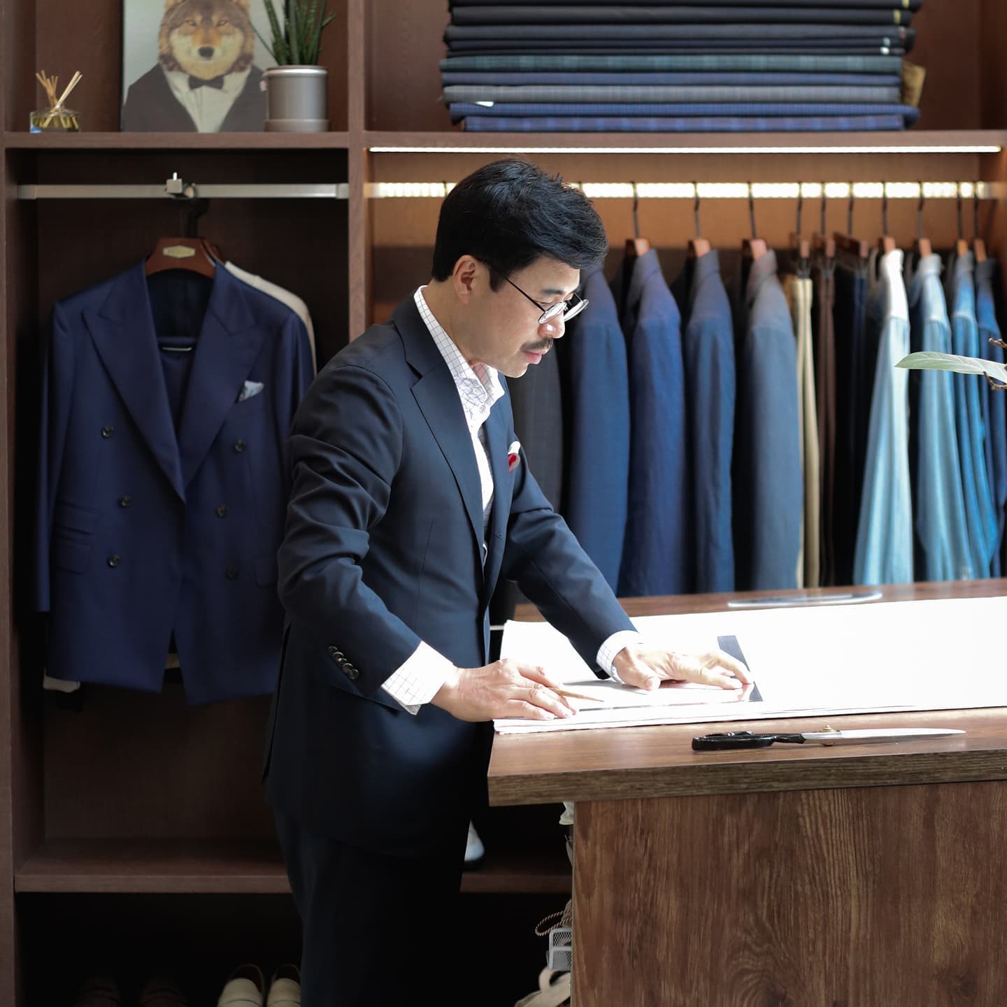 Tailor working with suit fabric on a wooden table